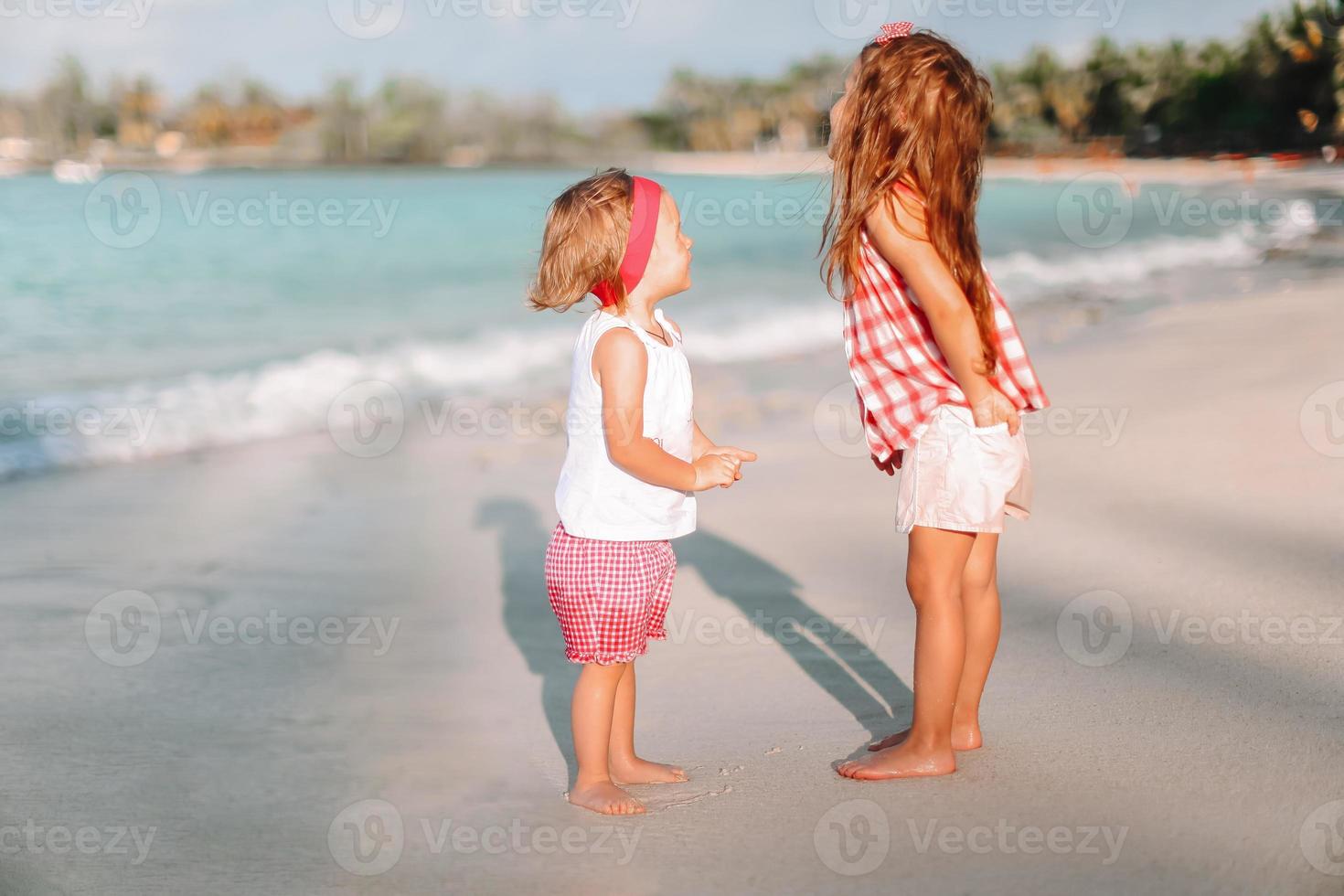 Little happy funny girls have a lot of fun at tropical beach playing together. photo