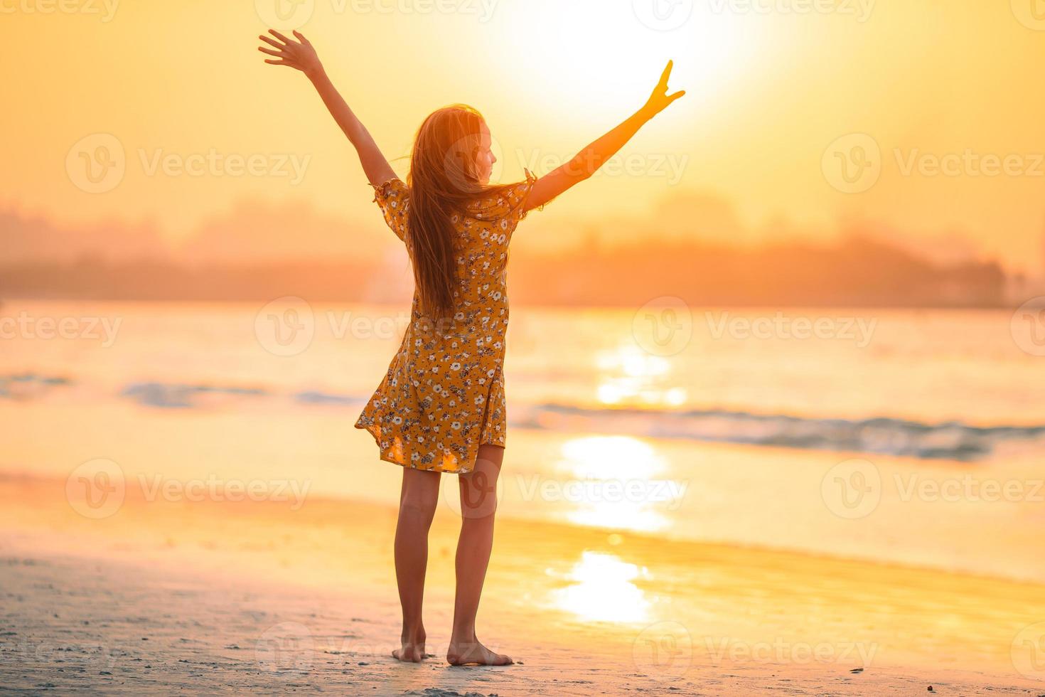 adorable niña feliz en la playa blanca al atardecer. foto