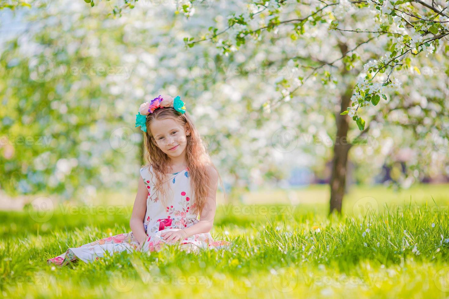 Adorable little girl in blooming apple garden on beautiful spring day photo