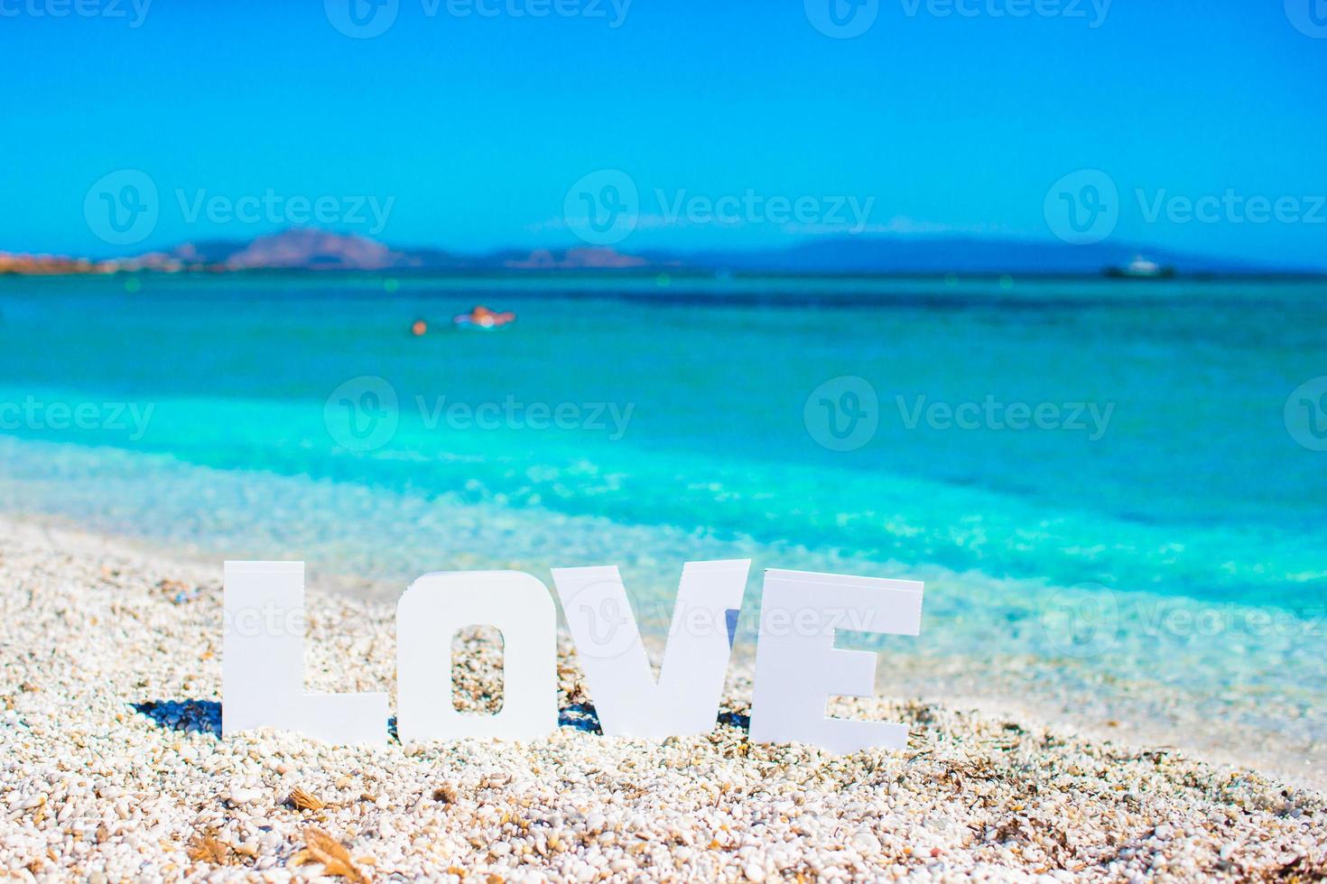 palabra amor en el fondo de la playa tropical del mar turquesa y el cielo azul foto