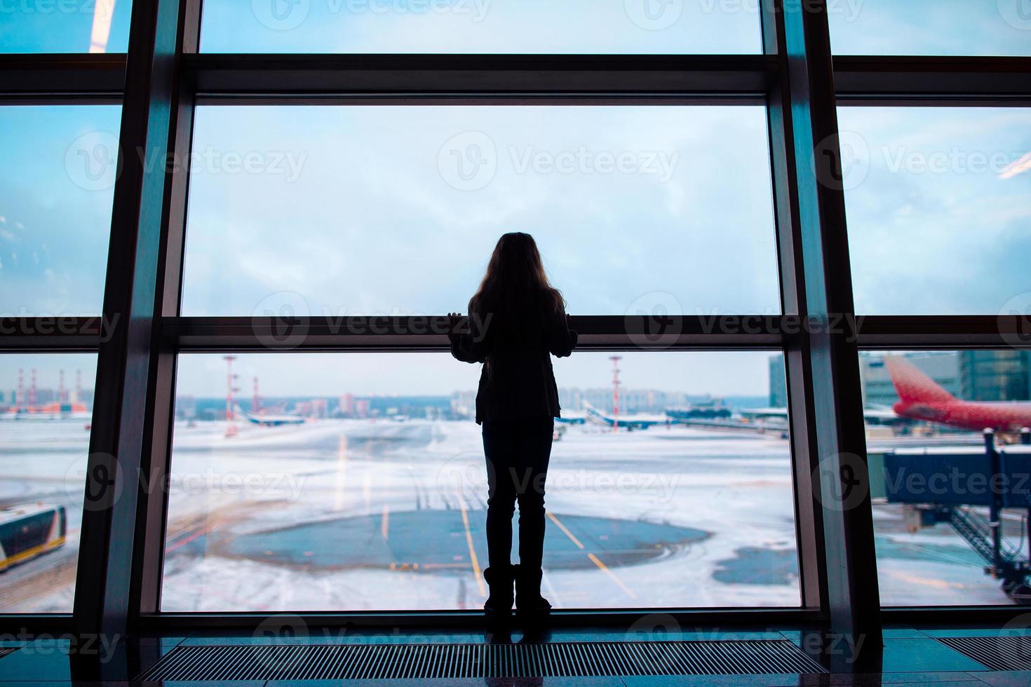 Little girl in airport near big window while wait for boarding photo