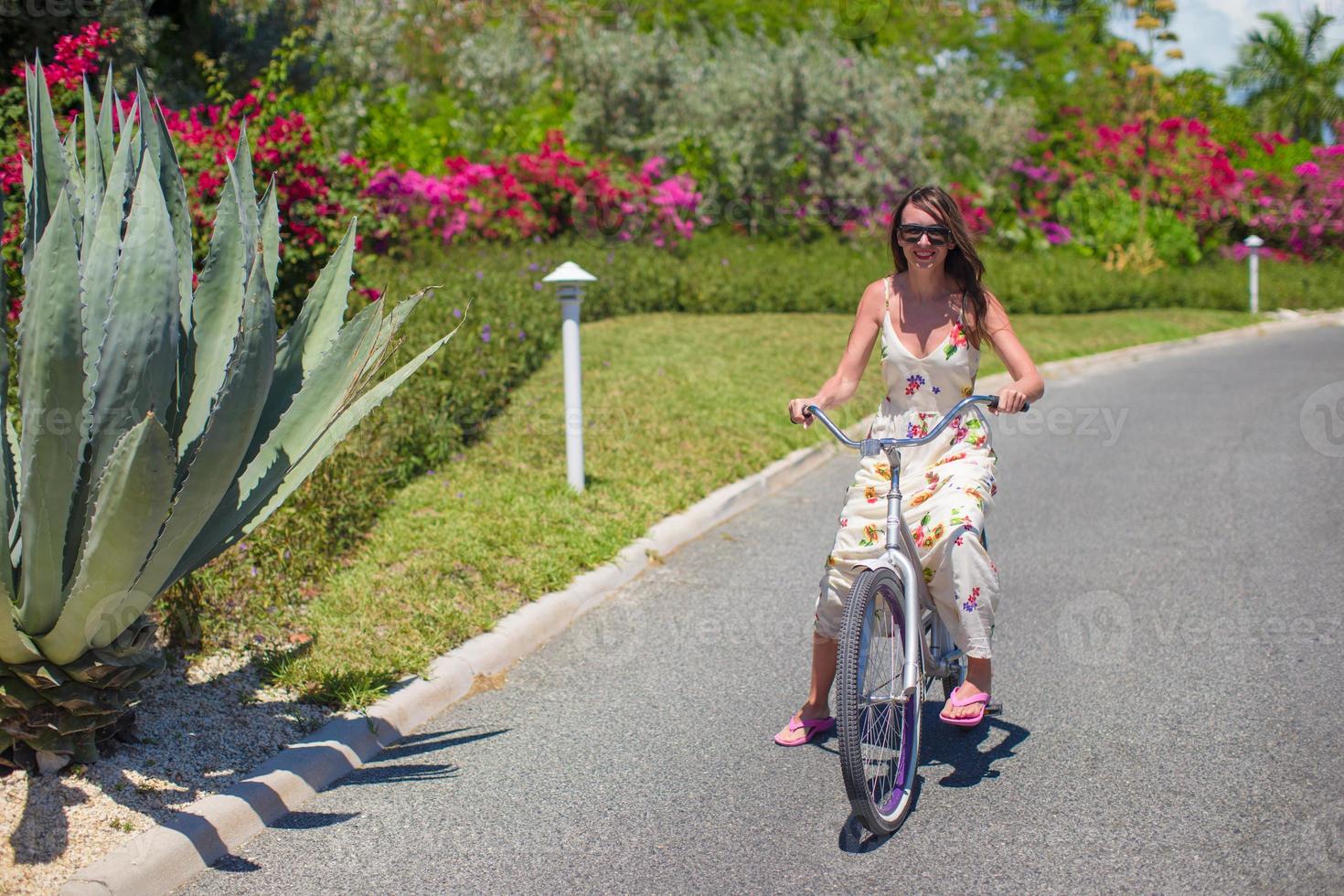 Young woman riding a bike on tropical resort photo