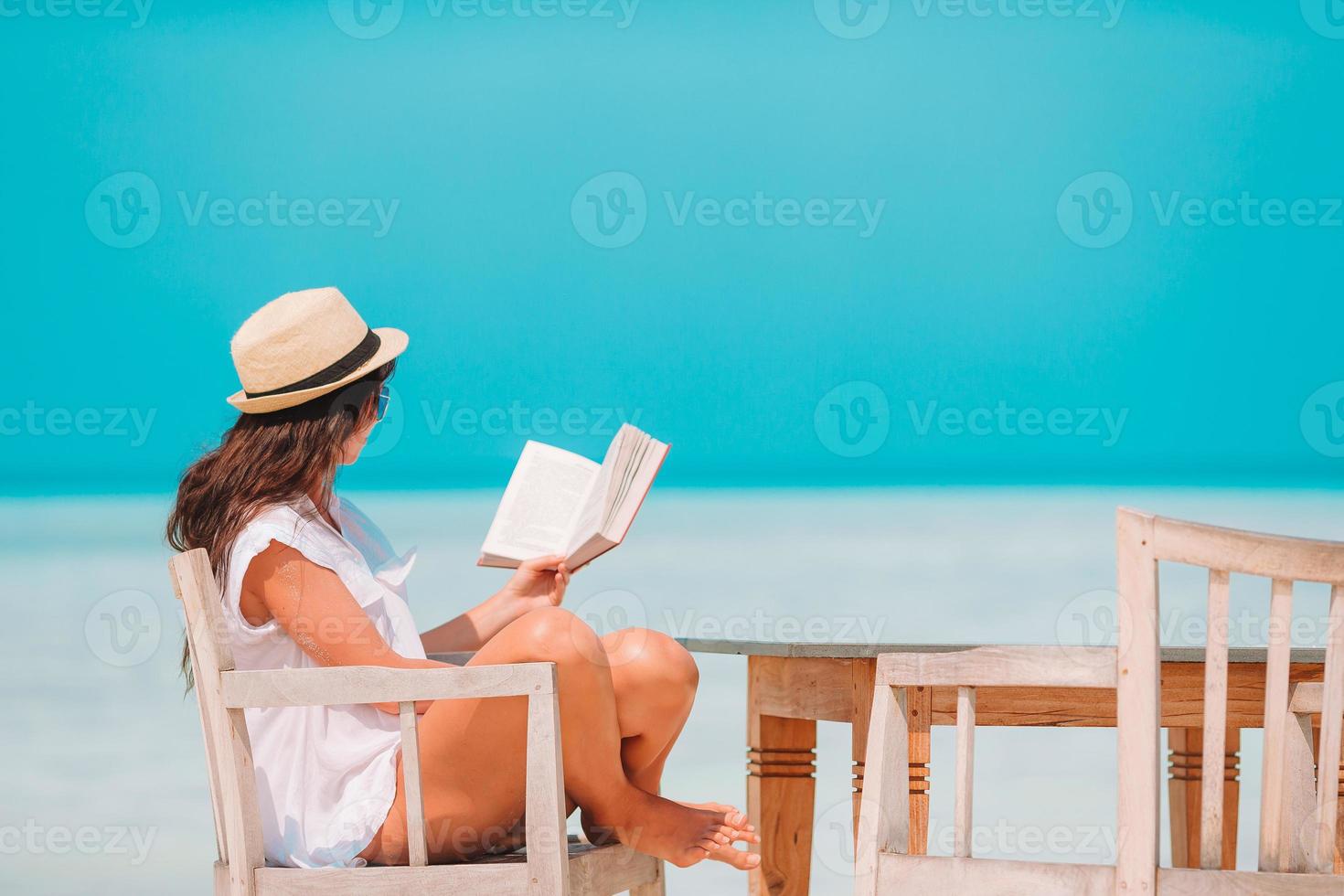 Young woman reading book during tropical white beach photo