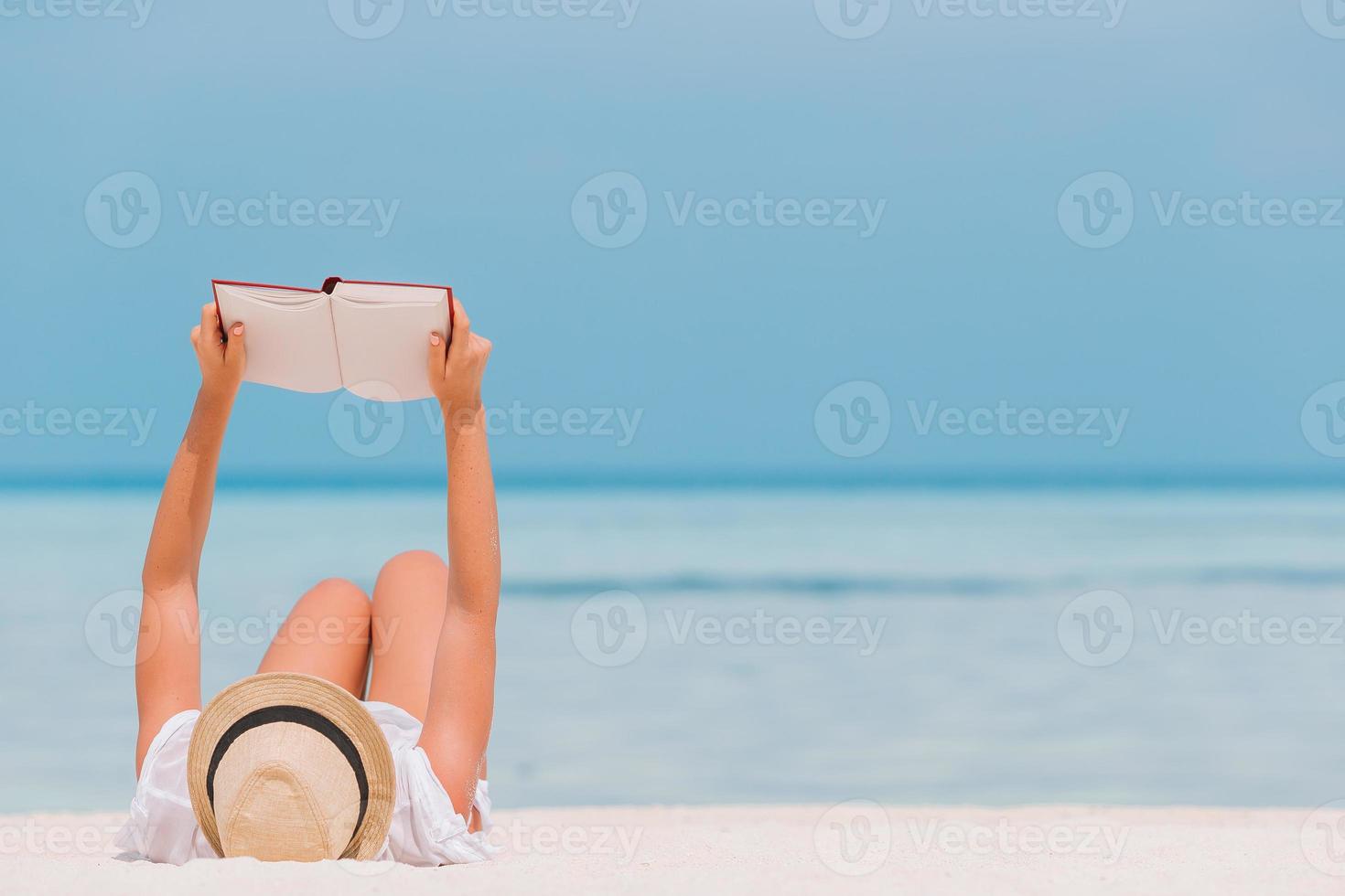 Young woman reading book during tropical white beach photo