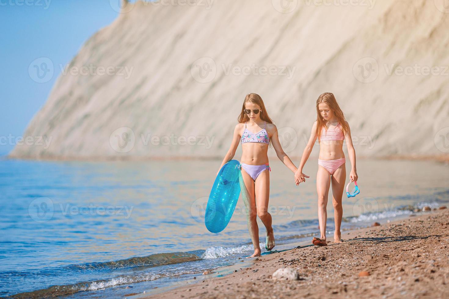 Little girls having fun at tropical beach during summer vacation playing together photo