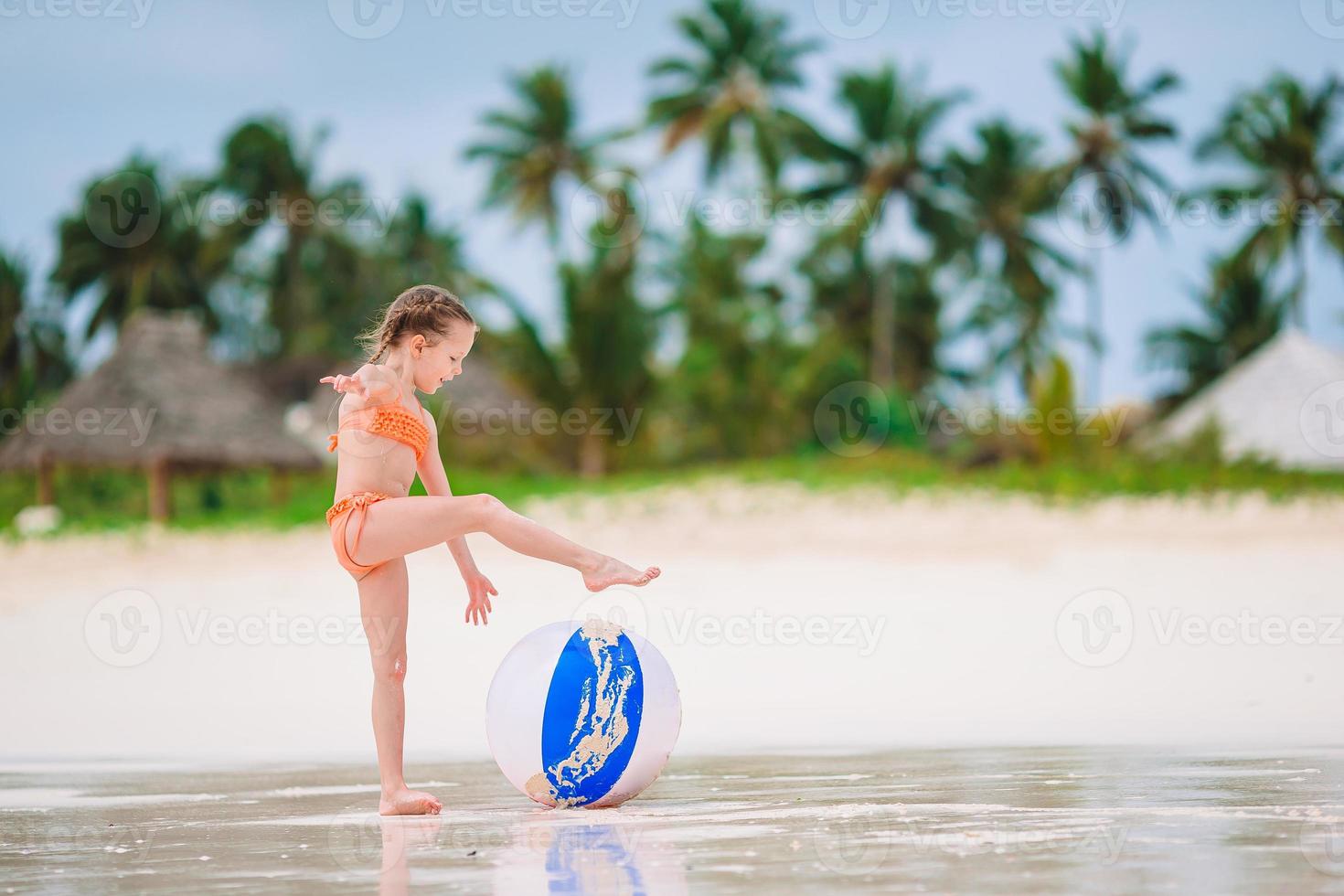 Little adorable girl playing on beach with ball photo