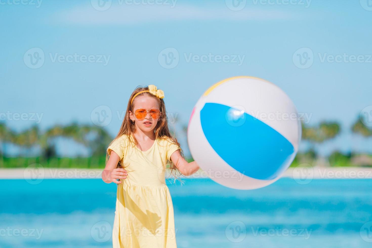 Little adorable girl playing on beach with ball photo