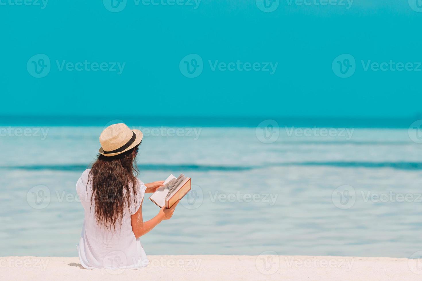 Portrait of a young woman relaxing on the beach, reading a book photo