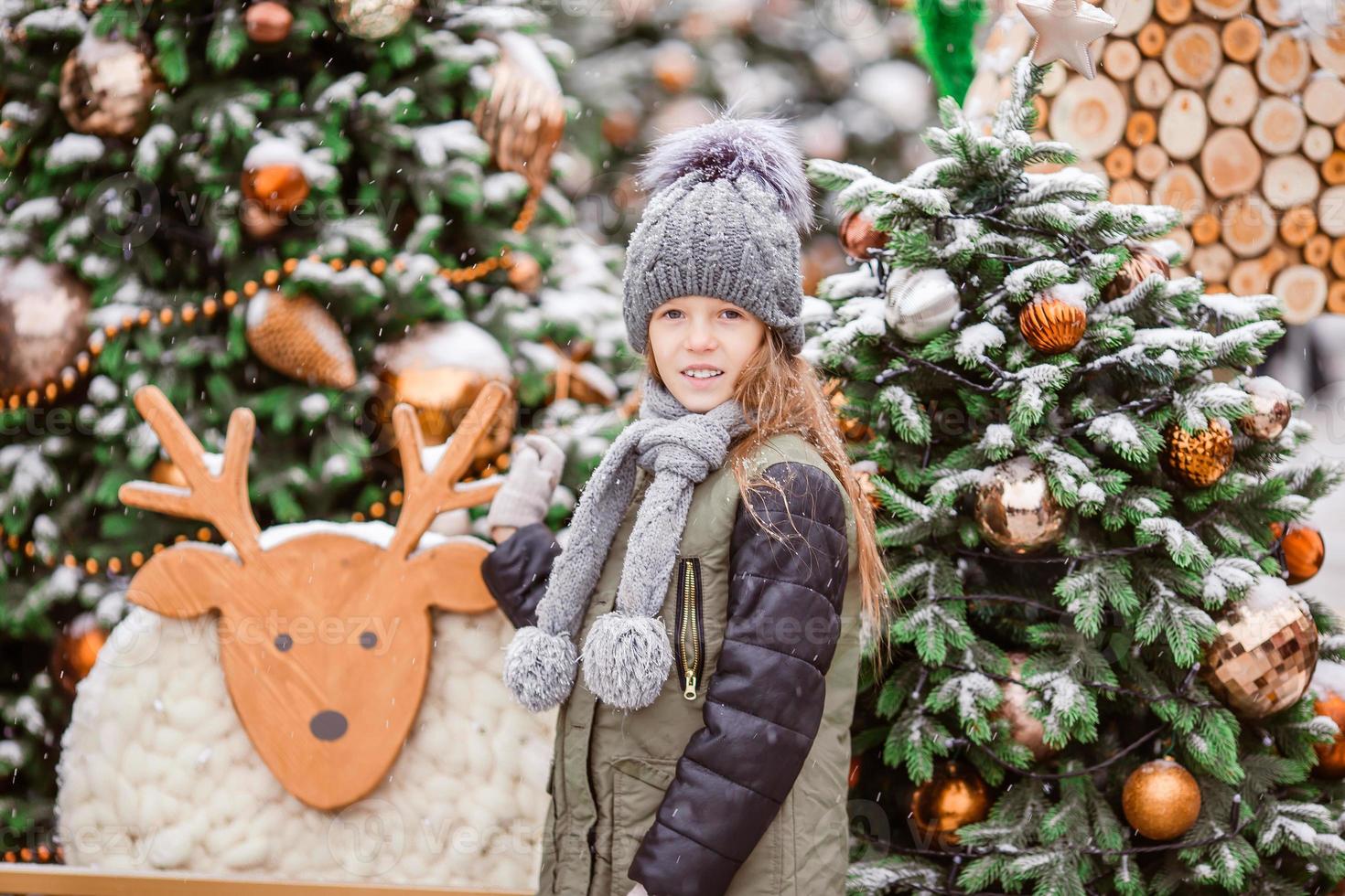 Little happy girl near fir-tree branch in snow for new year. photo