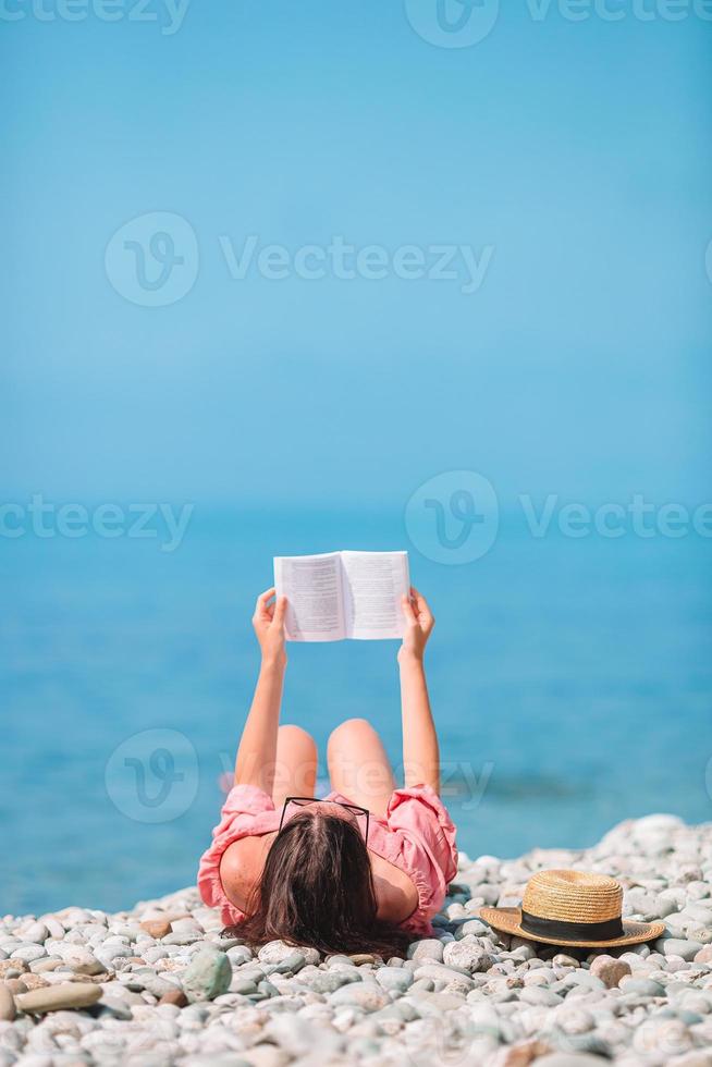 Young woman reading book during tropical white beach photo