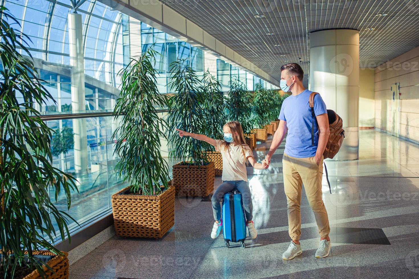 Dad and little girl with nedical masks at airport. Protection against Coronavirus and gripp photo