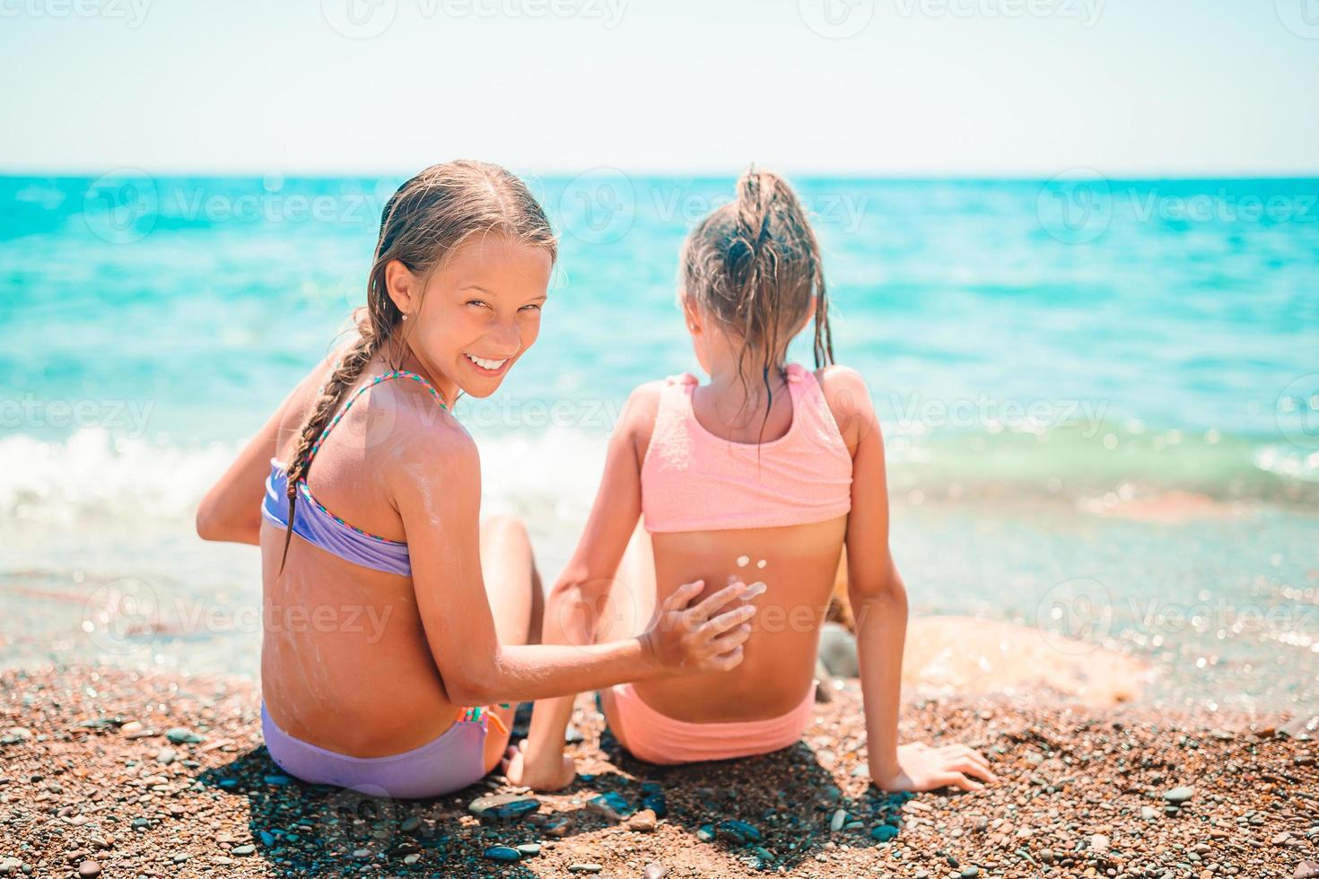UV protection. Sister puts sunscreen on her little sister's nose photo
