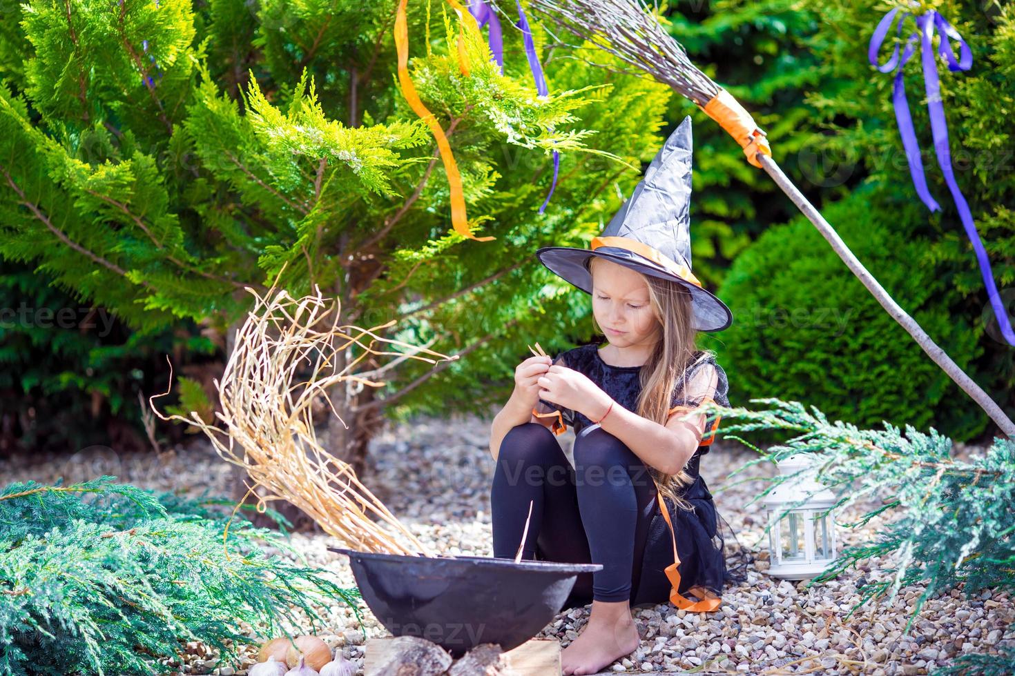 Happy little girl wearing witch costume on Halloween outdoors. Trick or treat. photo