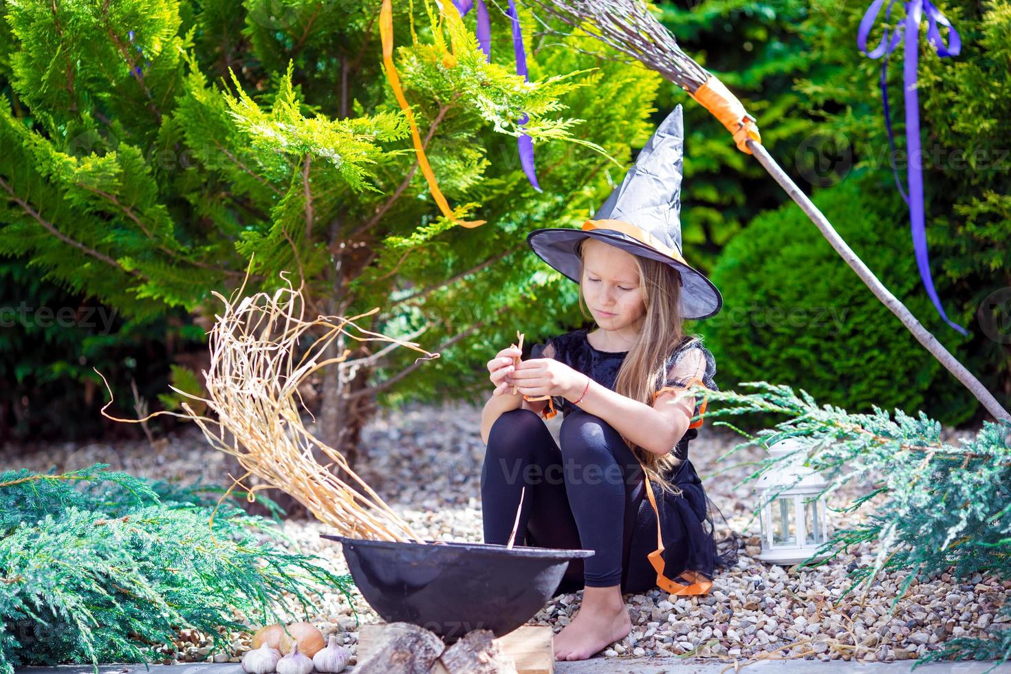 Adorable toddler girl wearing witch costume on Halloween outdoors. Trick or treat. photo