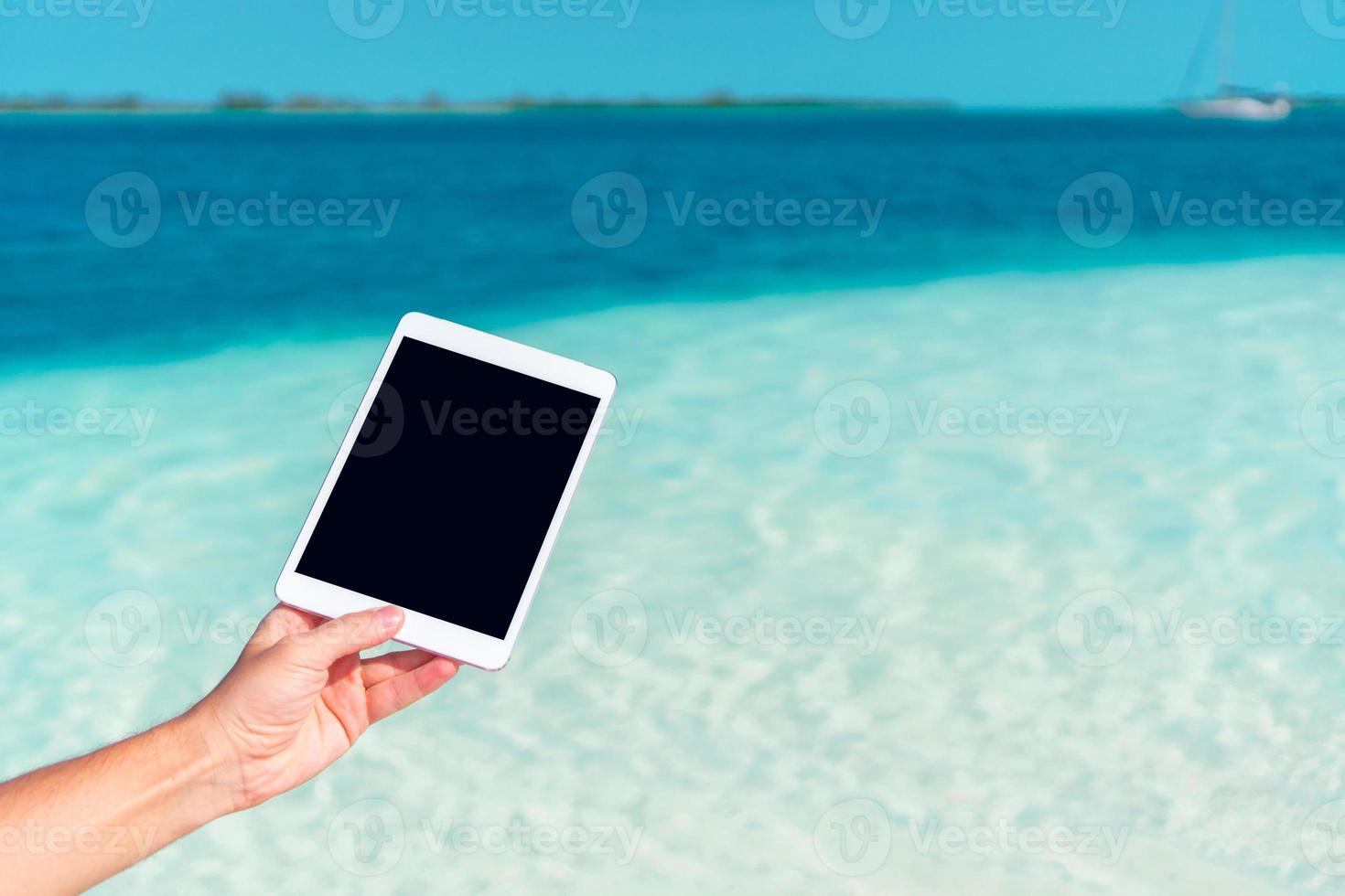 Close up laptop on the background of turquoise ocean at tropical beach photo