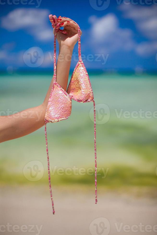Woman's hand holding pink bra background the sea photo