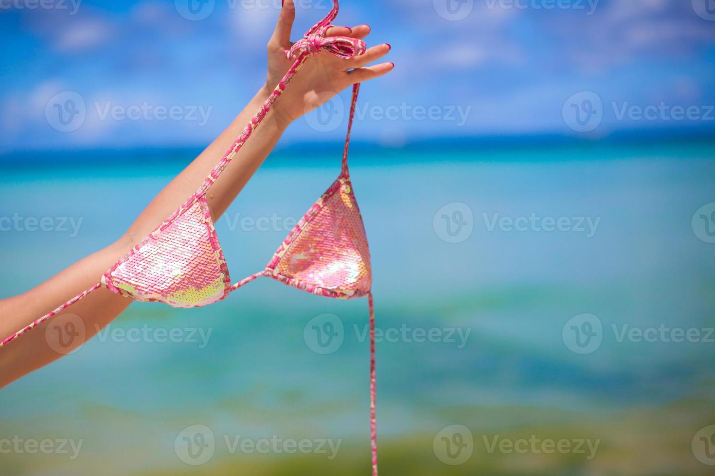 Woman hand holding pink bra isolated on exotic background photo