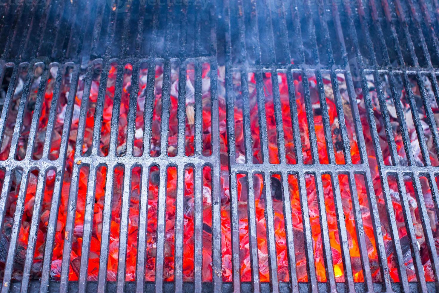 Empty black cast iron grill with hot red glowing coals photo