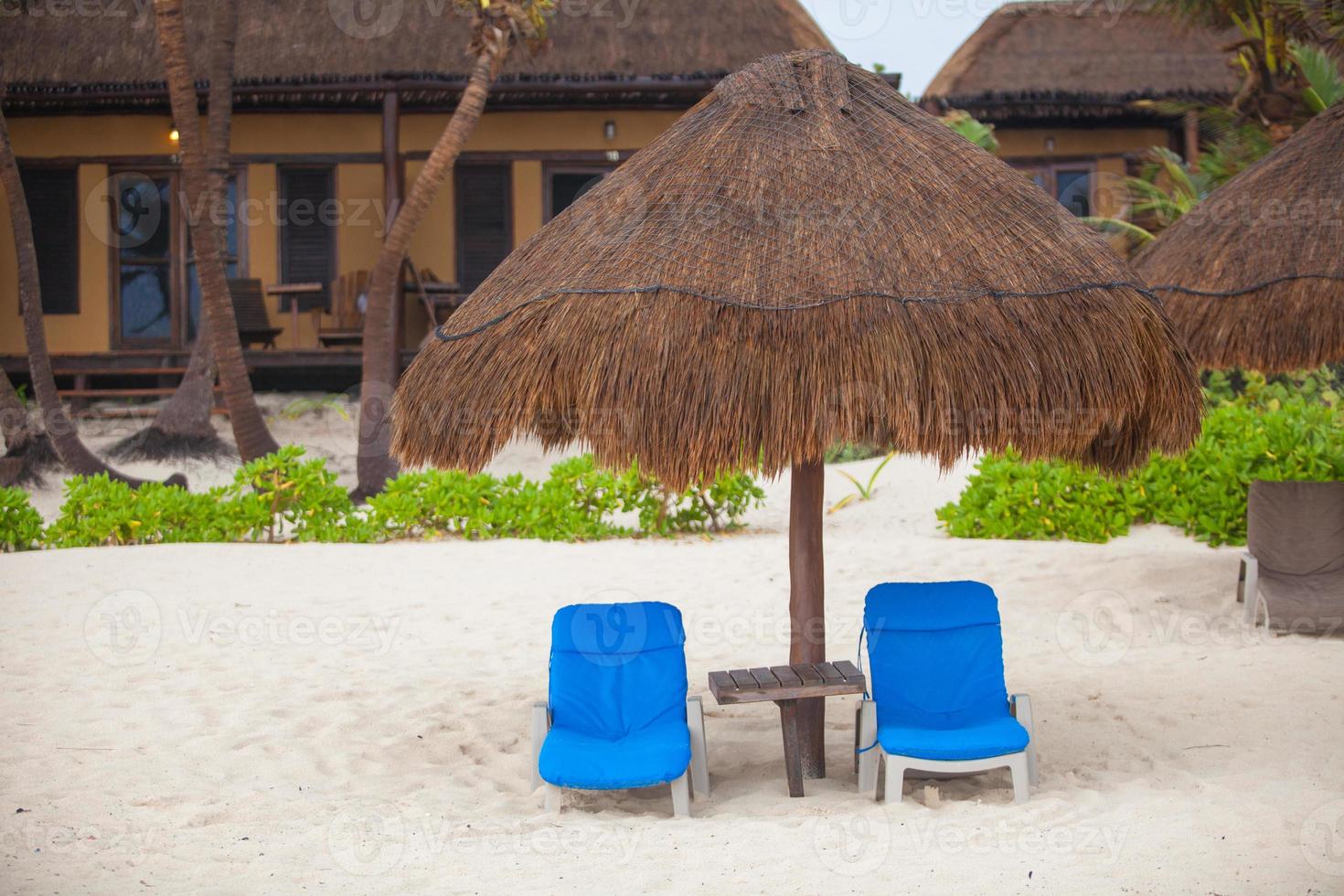 Blue beach loungers under thatched umbrellas on a rainy beach photo