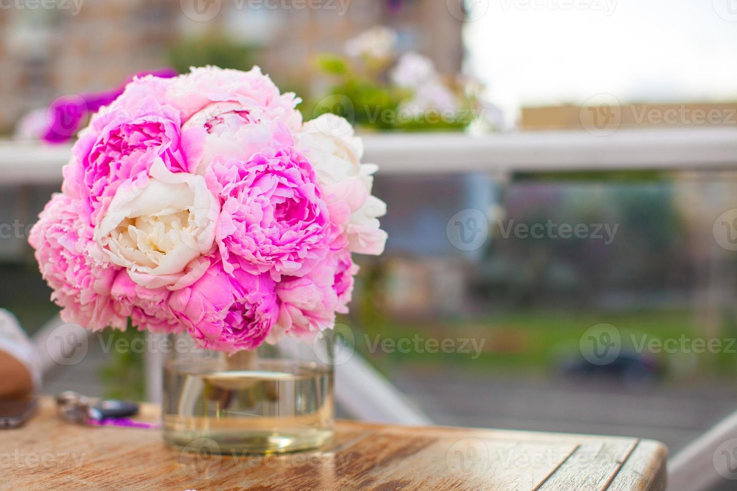 Charming bouquet of peonies in vase on table at restaurant photo