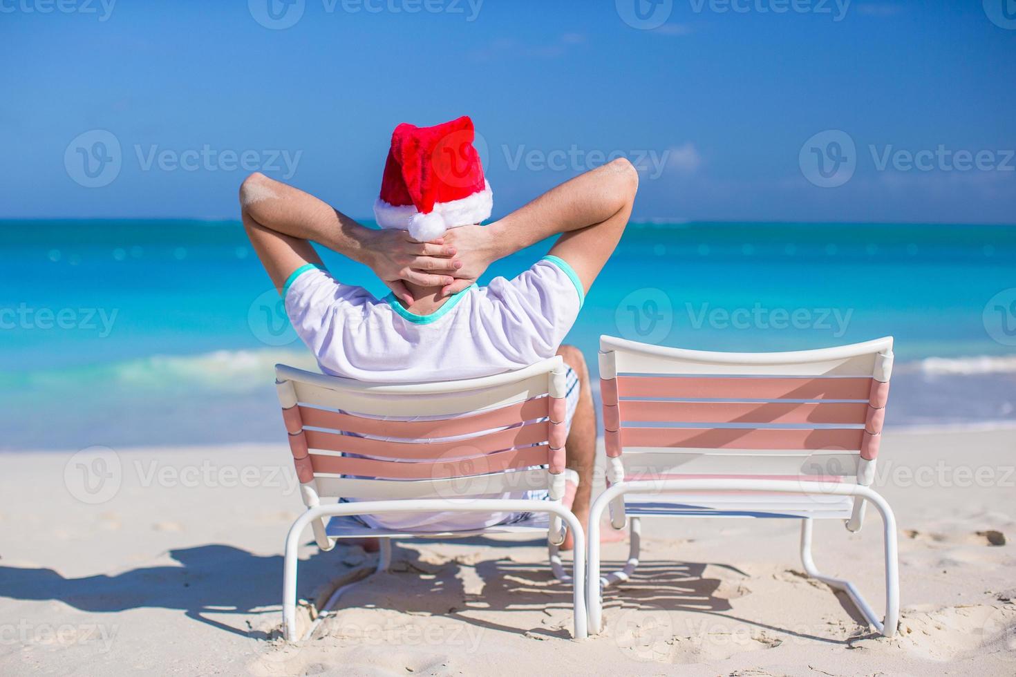 Back view of young man in Christmas hat at beach chair photo