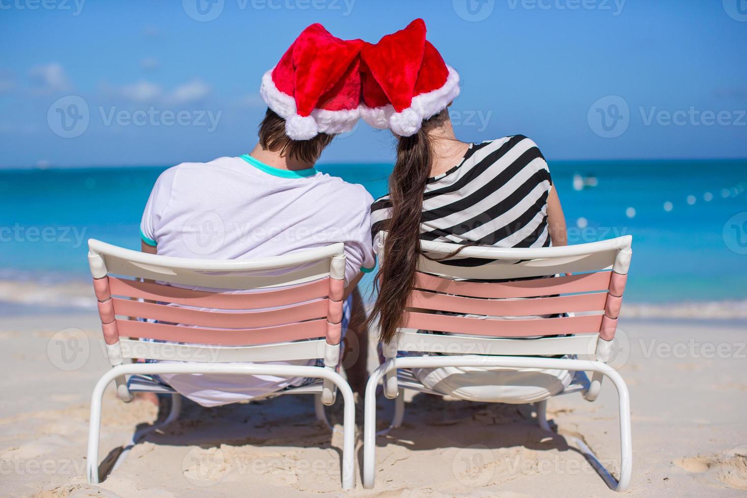 pareja joven con sombreros de santa disfruta de vacaciones en la playa foto