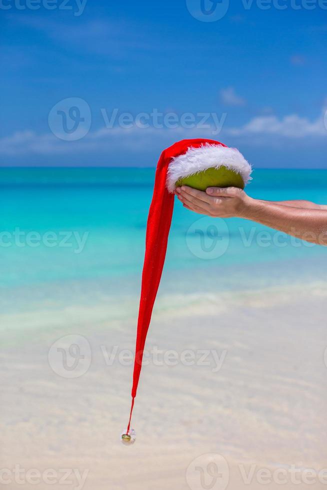 coco con sombrero de santa en manos masculinas contra el mar turquesa foto