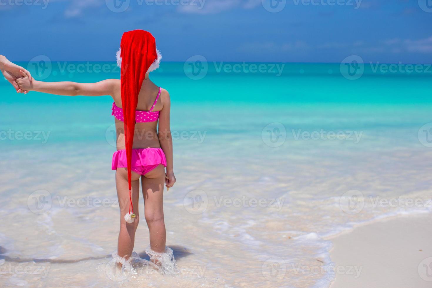niña linda en sombrero rojo de santa en playa tropical foto