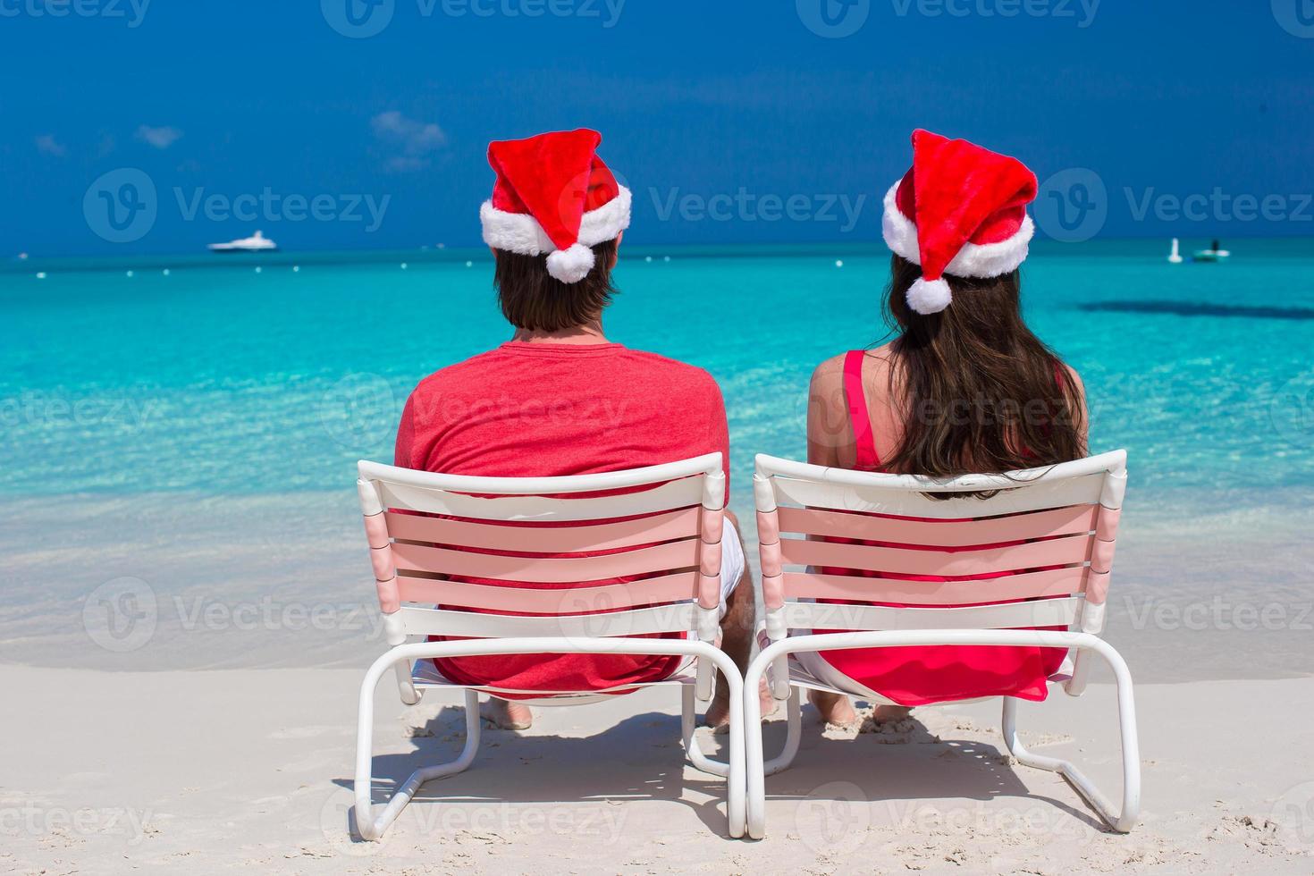 Happy romantic couple in red Santa Hats at tropical beach photo