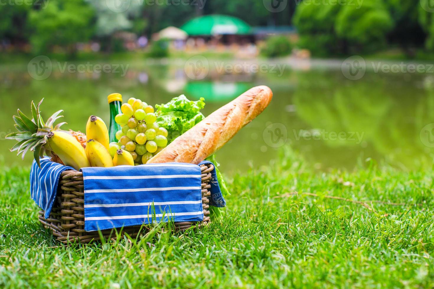 Picnic basket with fruits, bread and bottle of white wine photo