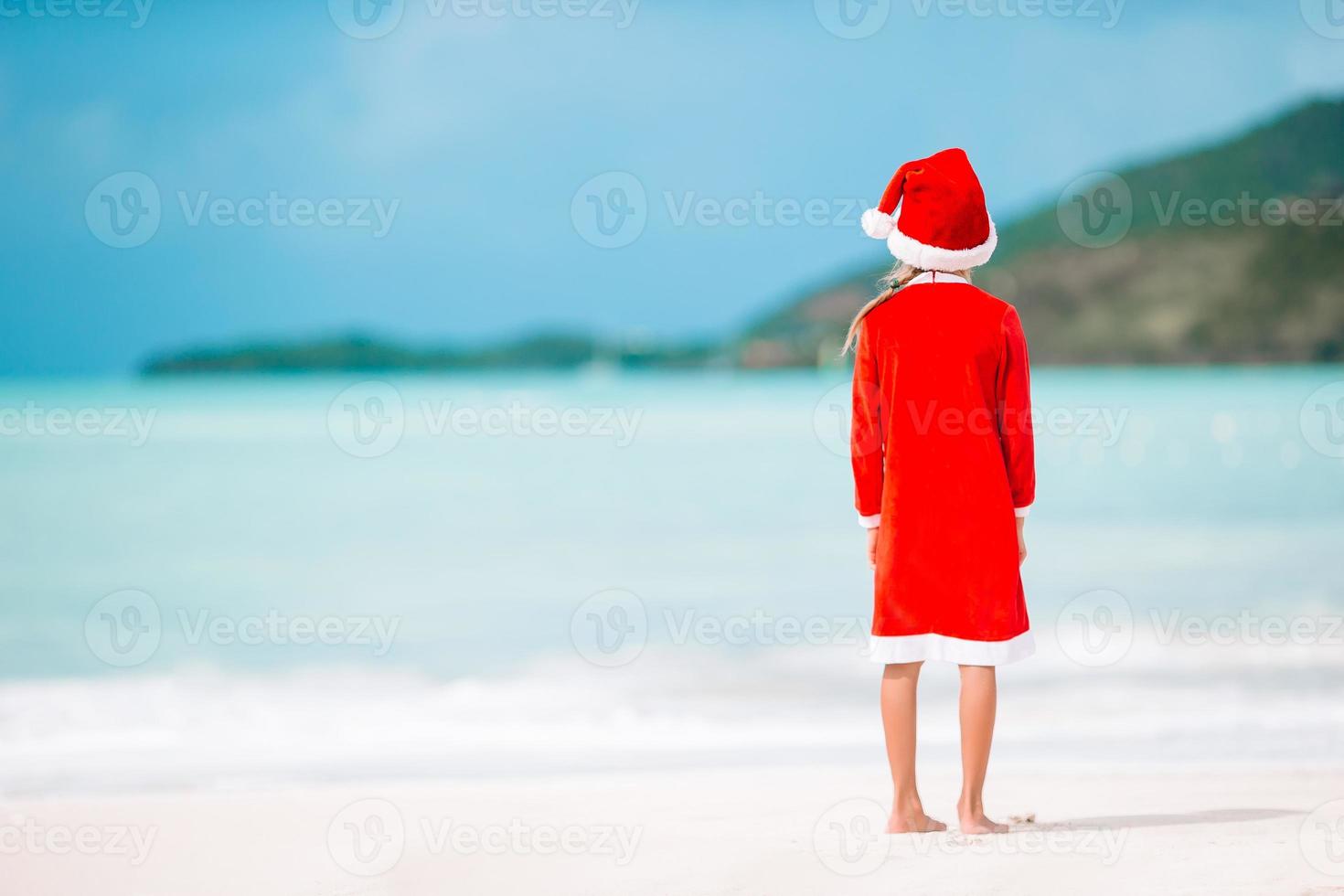 Adorable little girl in Santa hat on tropical beach photo