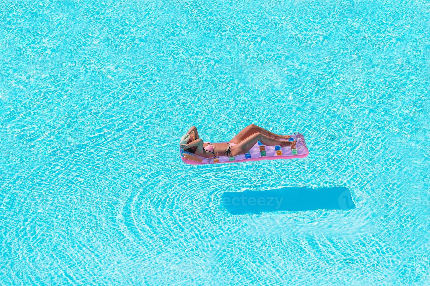 Young woman in bikini air mattress in the big swimming pool photo