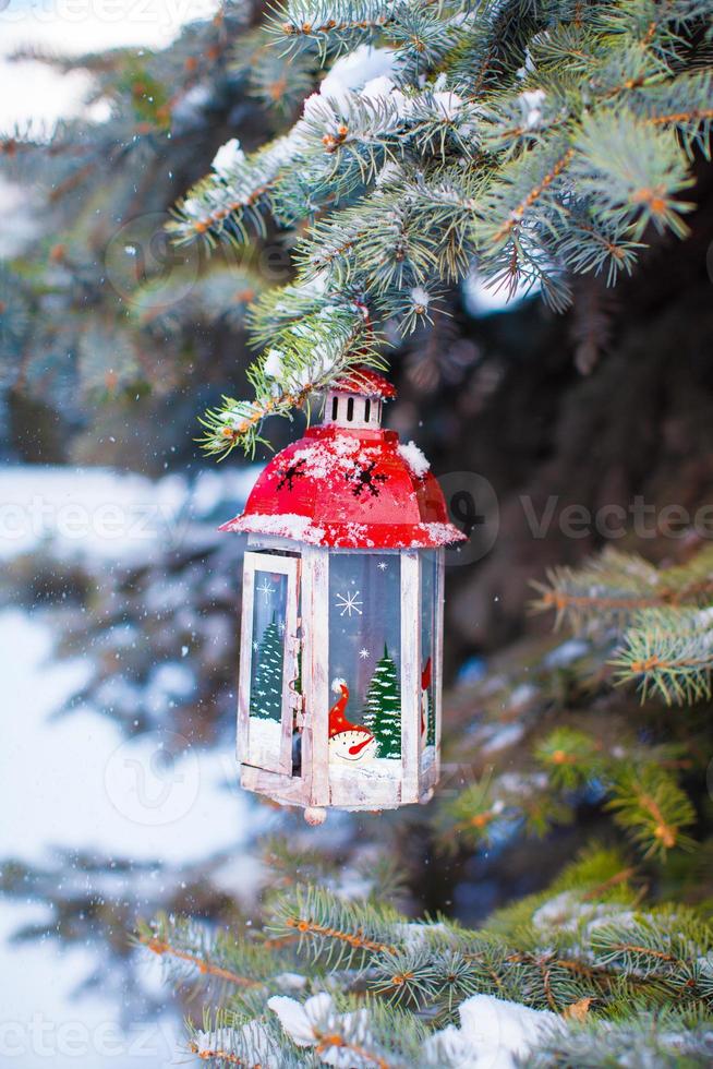 Christmas lantern with snowfall hanging on a fir branch photo