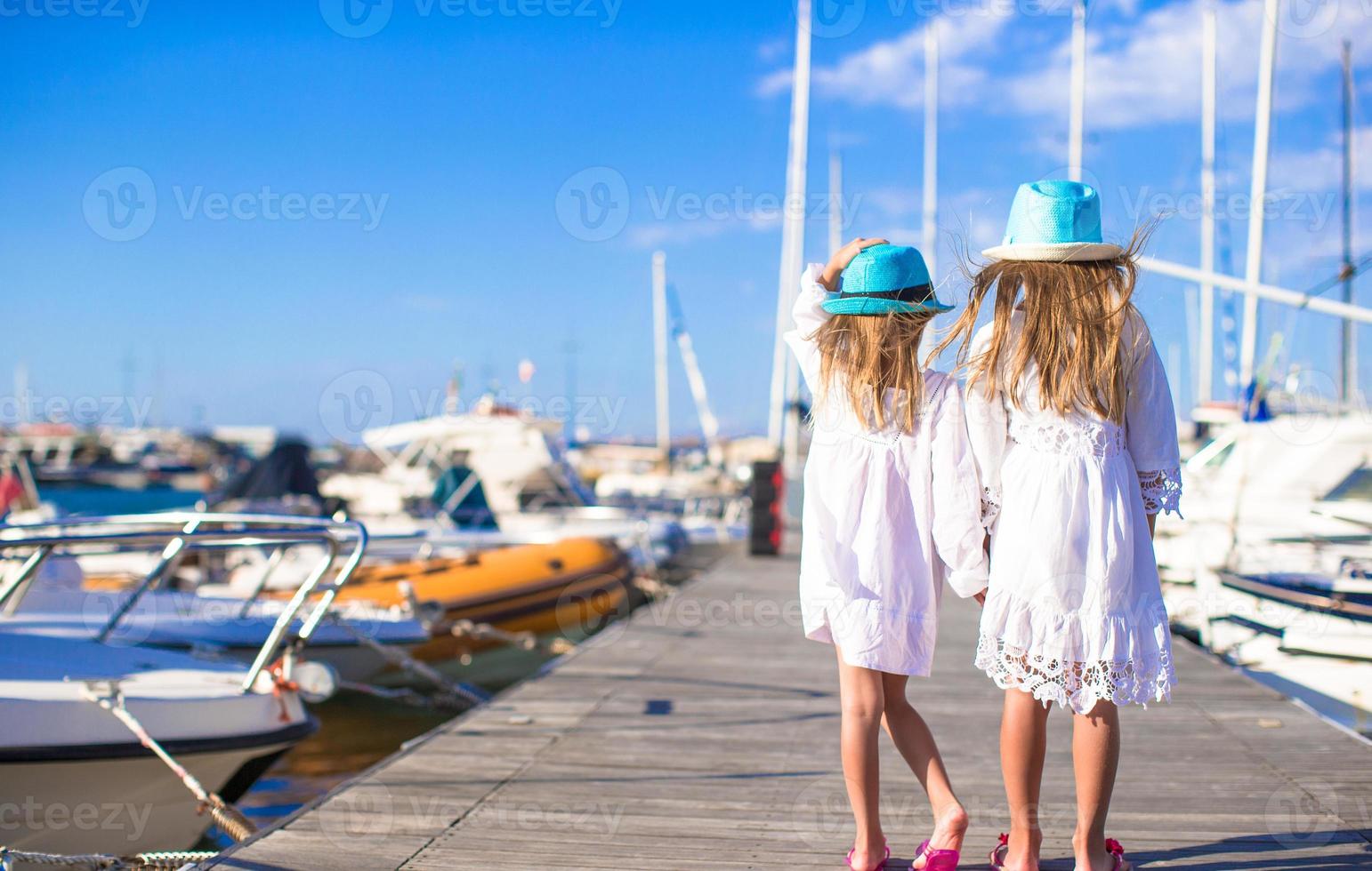 Adorable little girls walking in a port during summer vacation photo