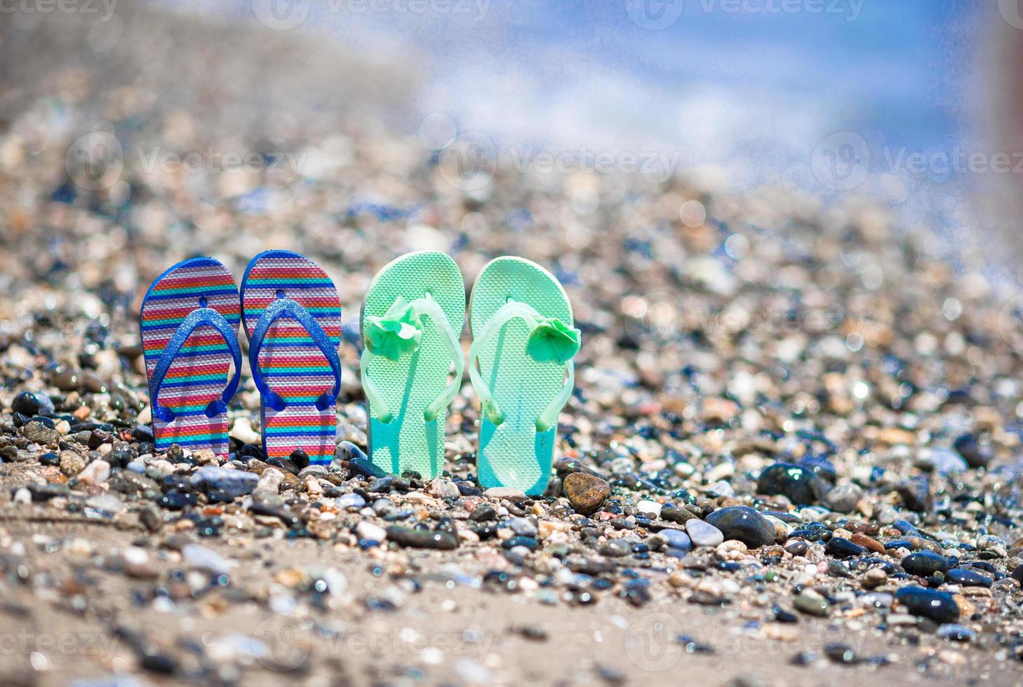 Kids flip flops on beach in front of the sea photo