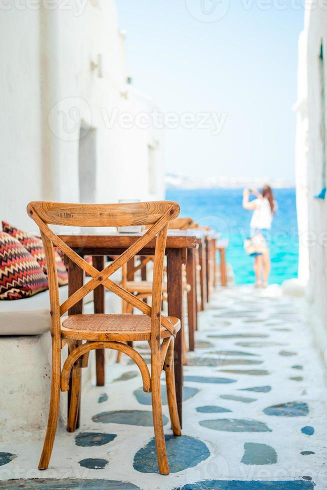 Benches with pillows in a typical greek outdoor cafe in Mykonos with amazing sea view on Cyclades islands photo