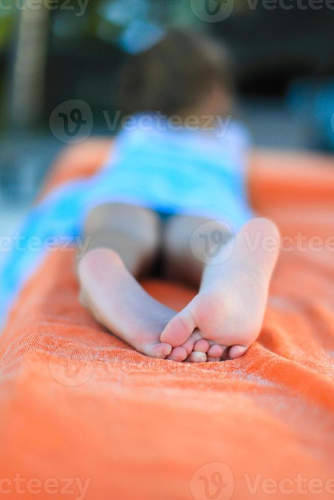 Closeup of little girl legs on tropical beach towel photo