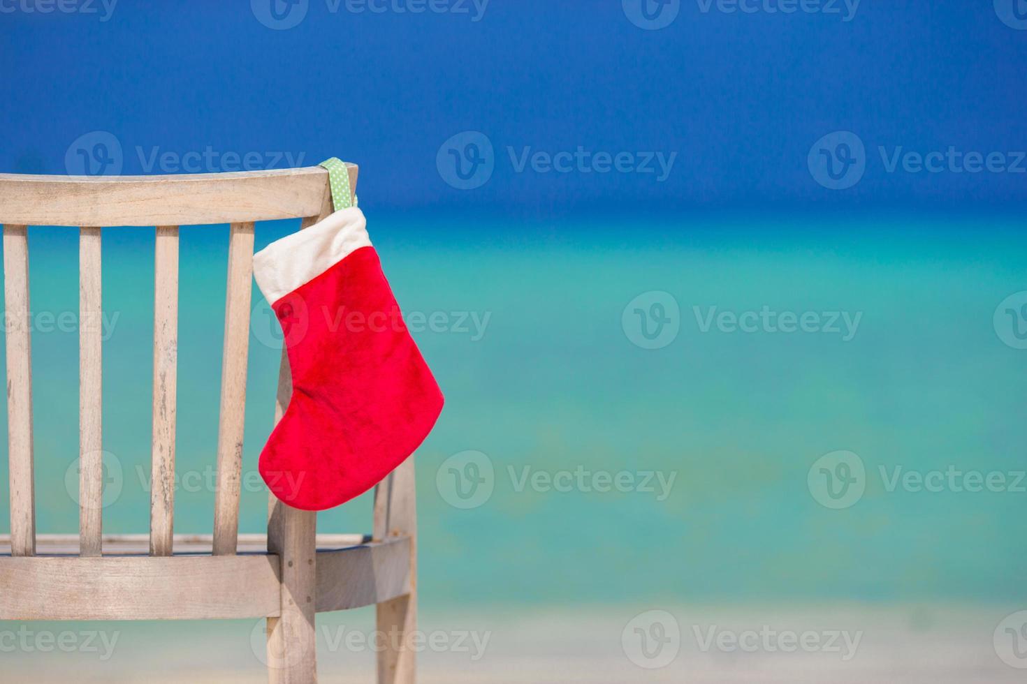 Red Christmas stocking on chair at outdoor cafe background the sea photo