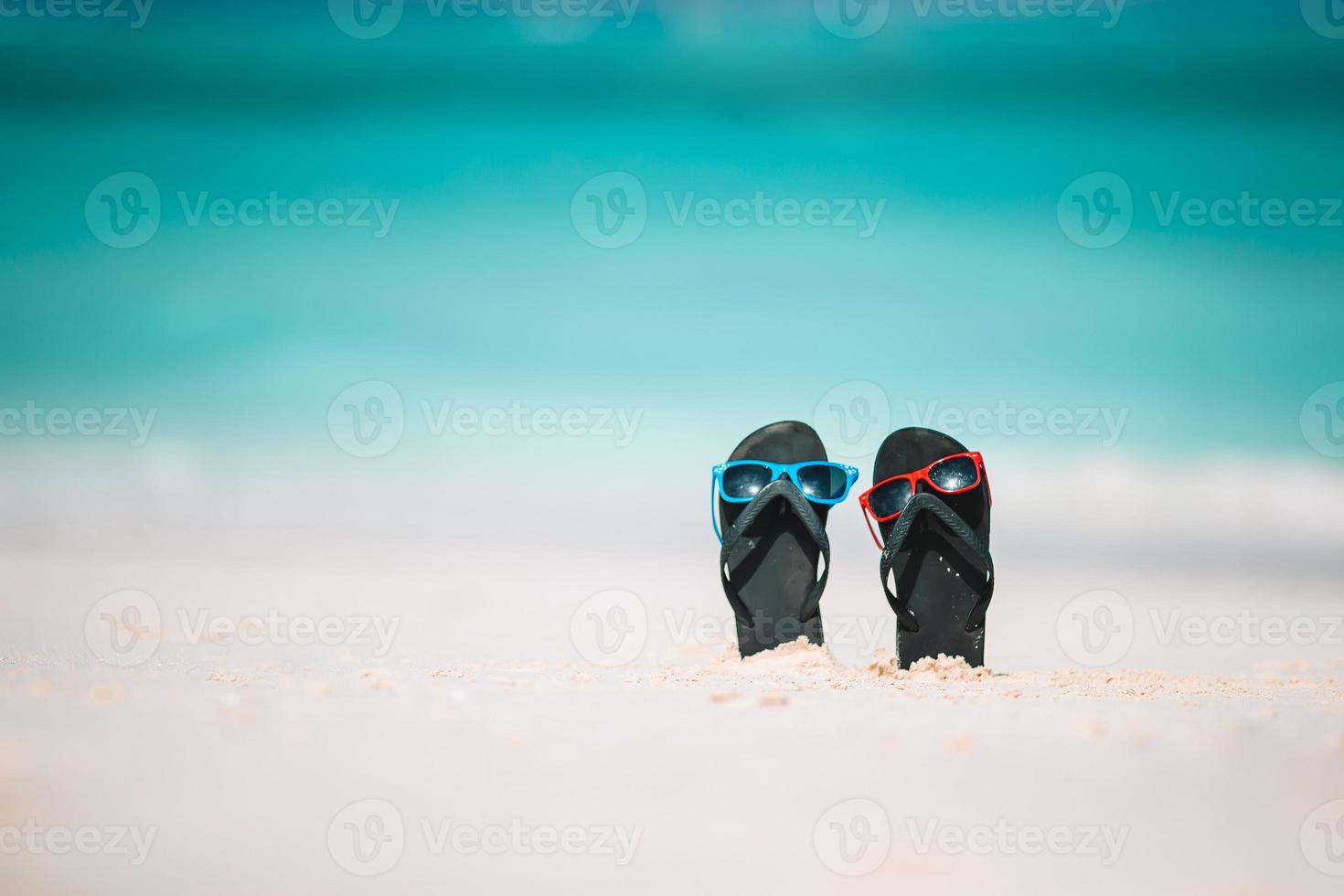 summer flip flops with sunglasses on sandy beach photo