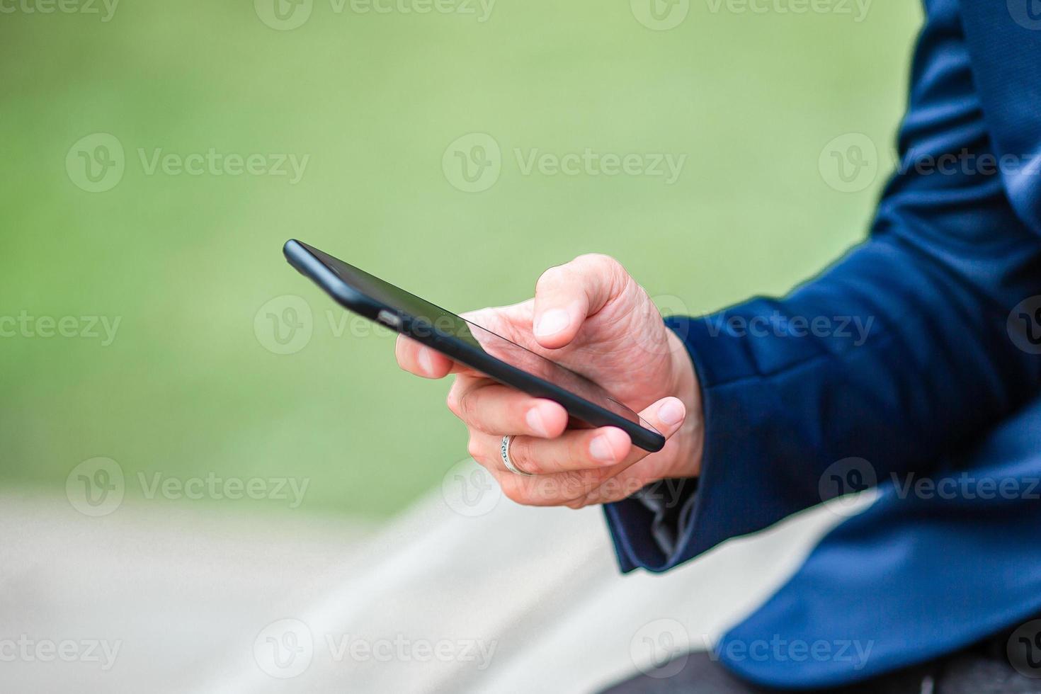el primer plano de las manos masculinas sostiene el celular al aire libre en la calle. hombre usando teléfono inteligente móvil. foto