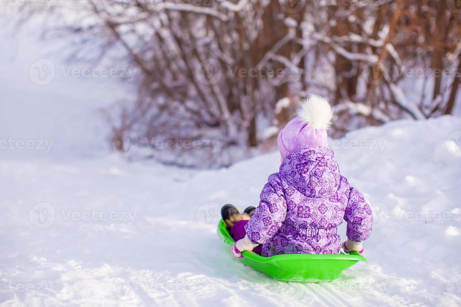 Little cute girl pulls a sled in warm winter day photo