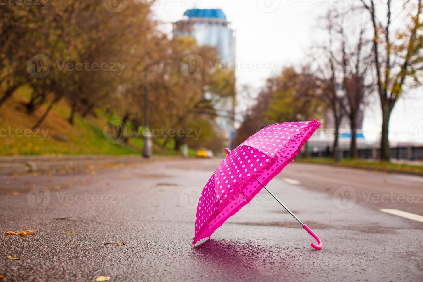 Pink children's umbrella on the wet asphalt outdoors photo