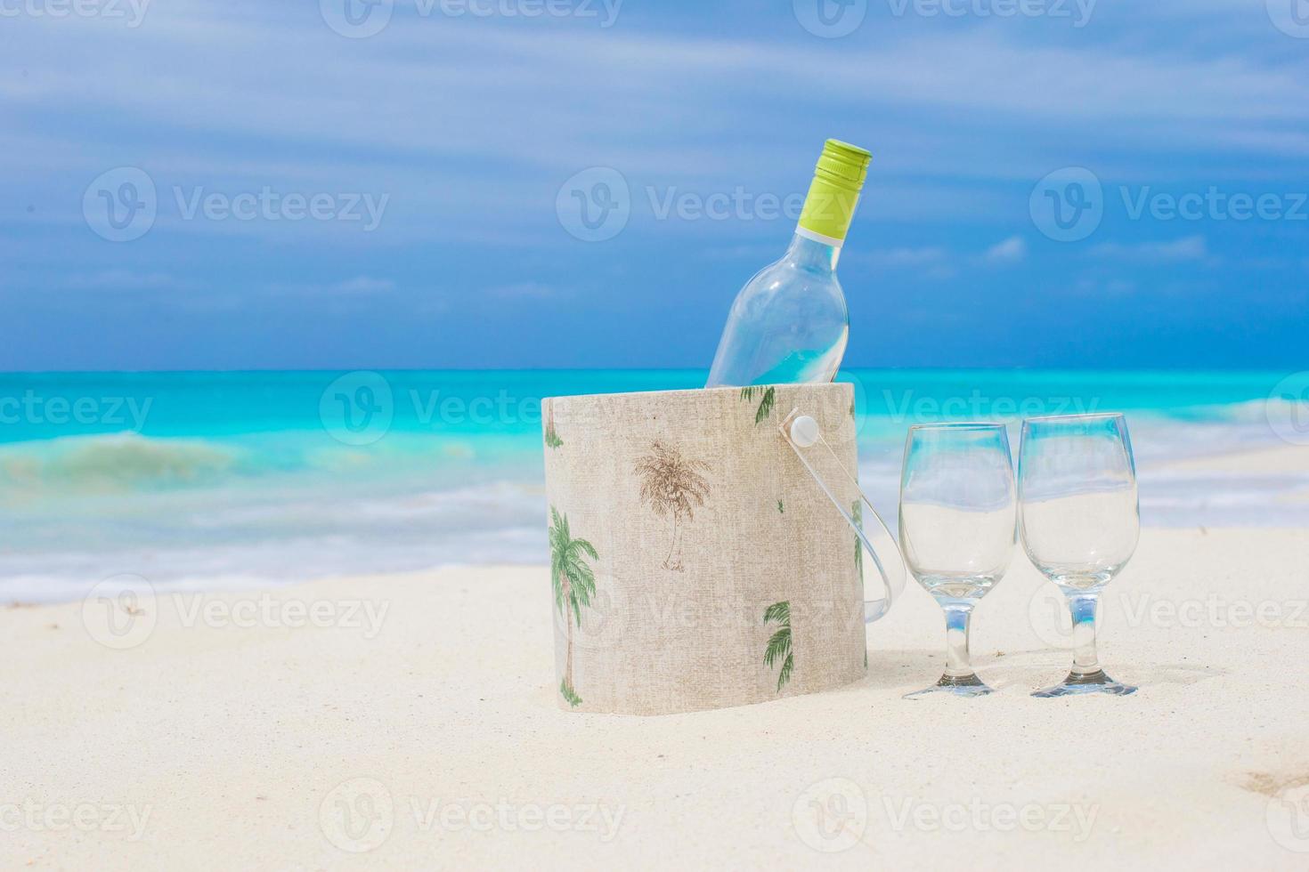 Bottle of white wine and two glasses on the exotic sandy beach photo