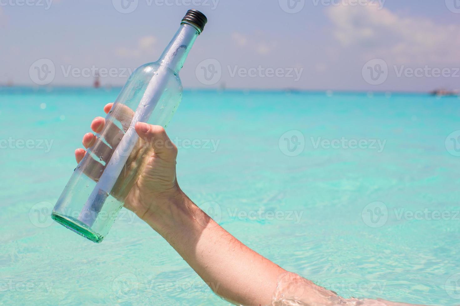 Bottle with a message in the hand background blue sky photo