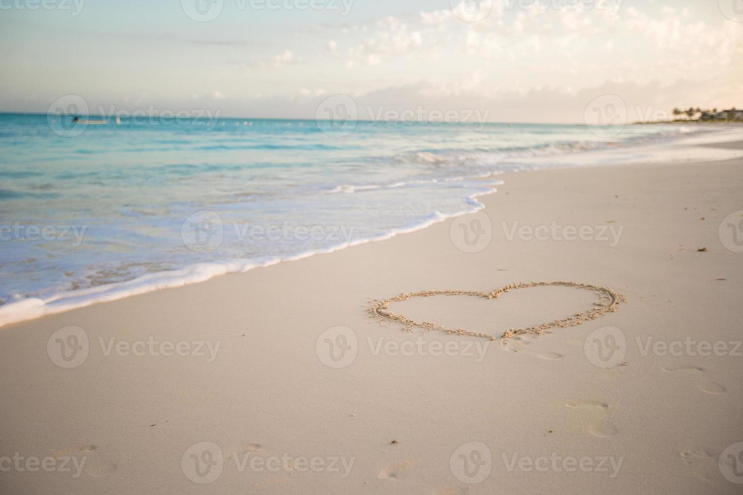 Heart painted in white sand on a tropical beach photo
