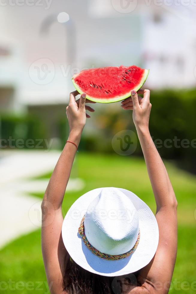 chica de primer plano con sombrero y gafas de sol con sandía relajándose cerca de la piscina foto