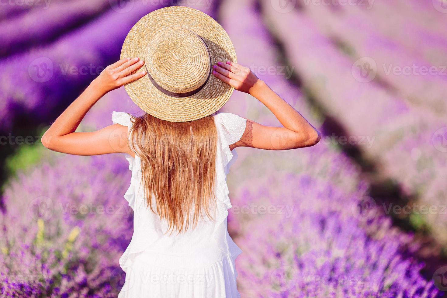 Woman in lavender flowers field at sunset in white dress and hat photo