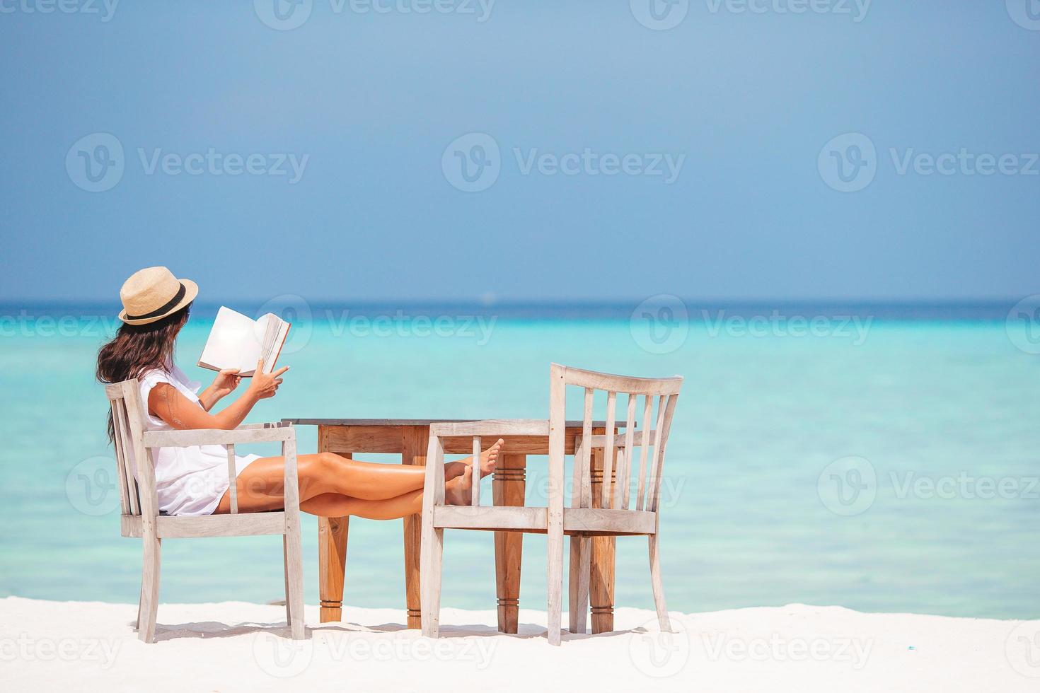 Young woman reading book during tropical white beach photo