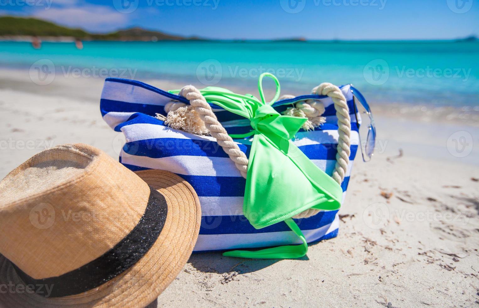 Stripe bag, straw hat, sunblock and towel on white tropical beach photo