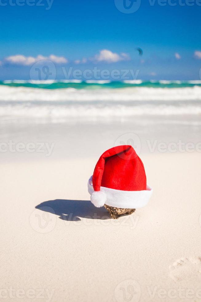 Santa Claus hat on the white sandy coast photo